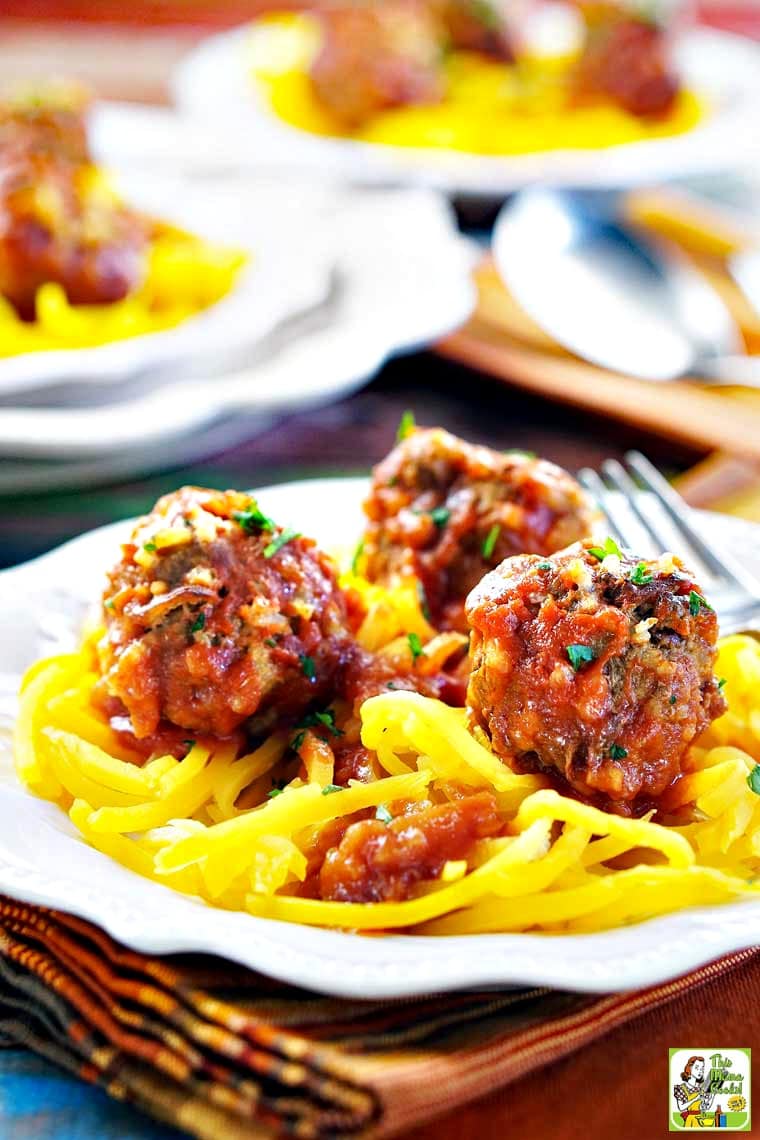 Closeup of a white plate of porcupine meatballs served on butternut squash noodles with tomato sauce.