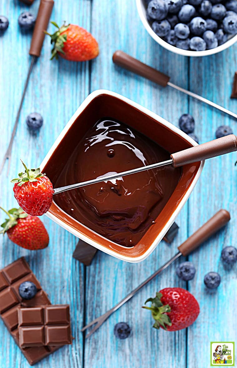  tomada de fondue de chocolate numa panela de fondue de cerâmica branca com um morango num espeto de fondue.