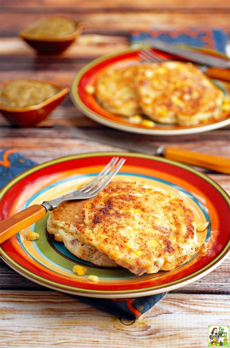 Corn fritters on a striped plate with a fork and napkin.