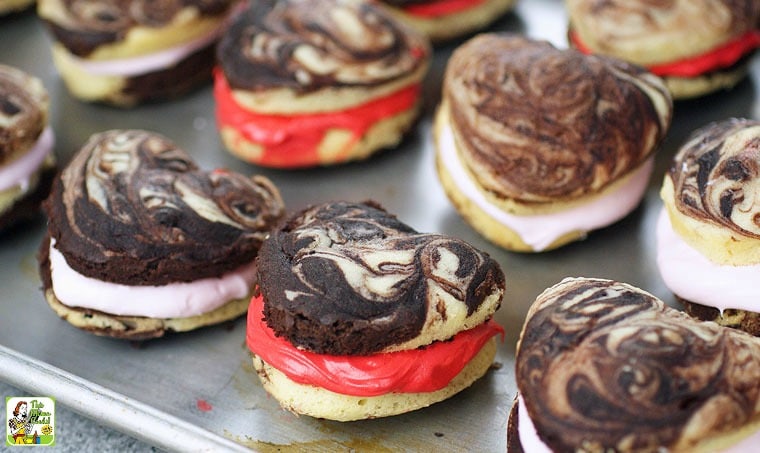 Cake mix whoopie pies filled with pink and red marshmallow cream on a baking tray.