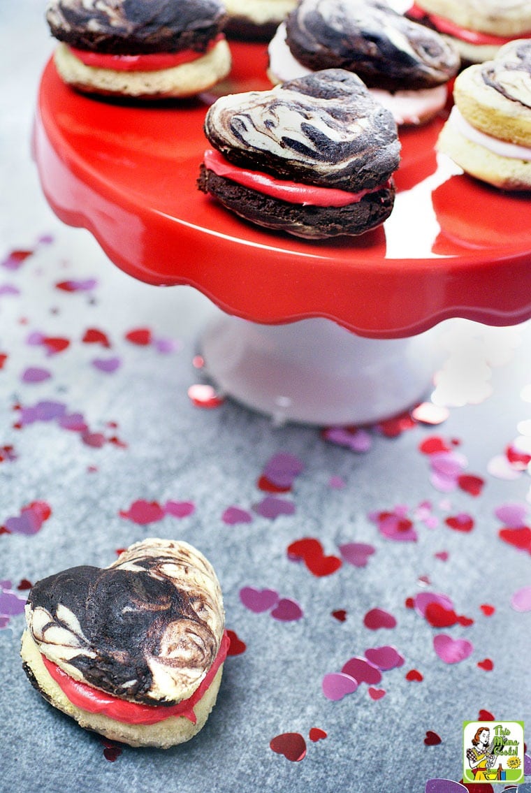 Heart shaped cake mix whoopie pies with red and pink marshmallow filing on a red and white cake stand.