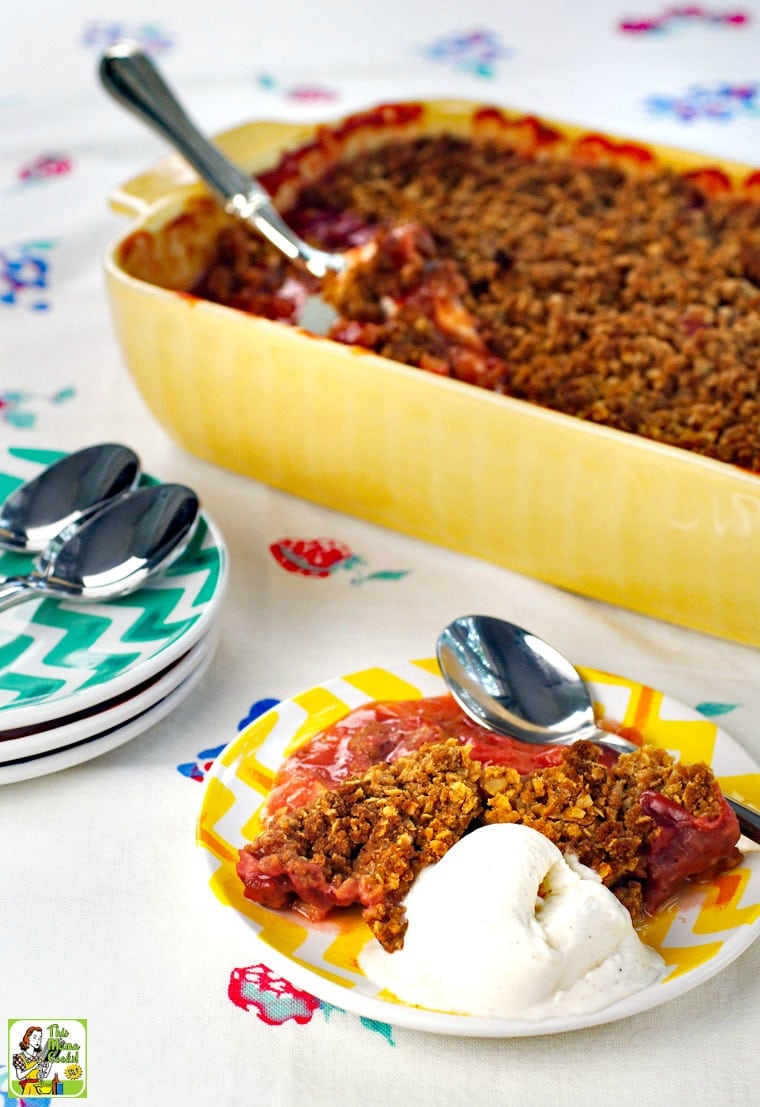 A small  plate of rhubarb crisp and a scoop of vanilla ice cream and a 9 x 13 casserole dish rhubarb crisp with more plates and spoons.