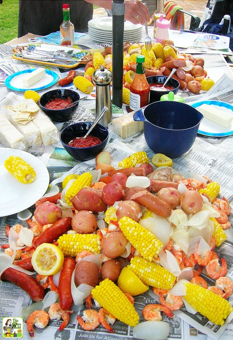 A party table with a spread of Cajun seafood boil with potatoes, corn, lemons, shrimp, and sausage.