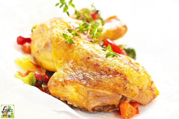 Smoked chicken leg and thigh quarters with herbs and vegetables on a white plate.