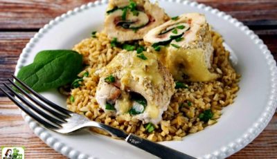 A white plate with three pieces of sliced chicken cordon bleu served on rice with a fork.