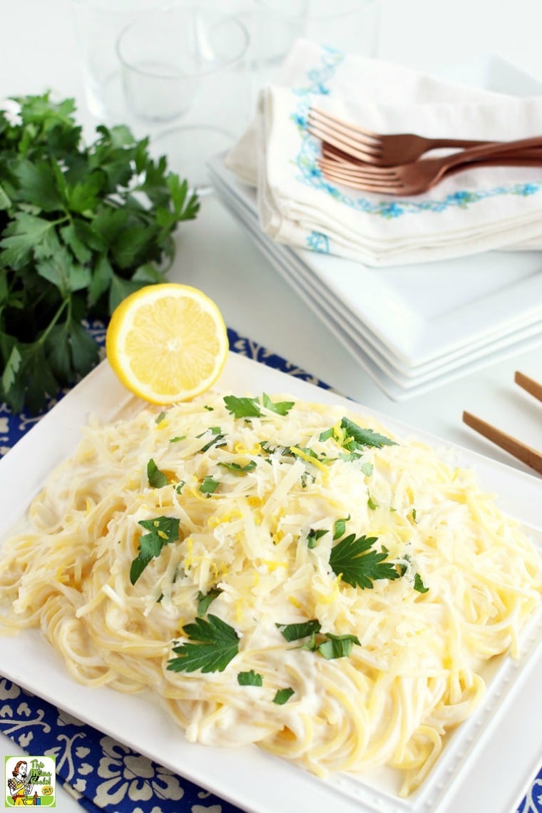 A dish of Lemon Pasta with grated cheese, a sprinkle of parsley, and some lemon zest on a white plate.