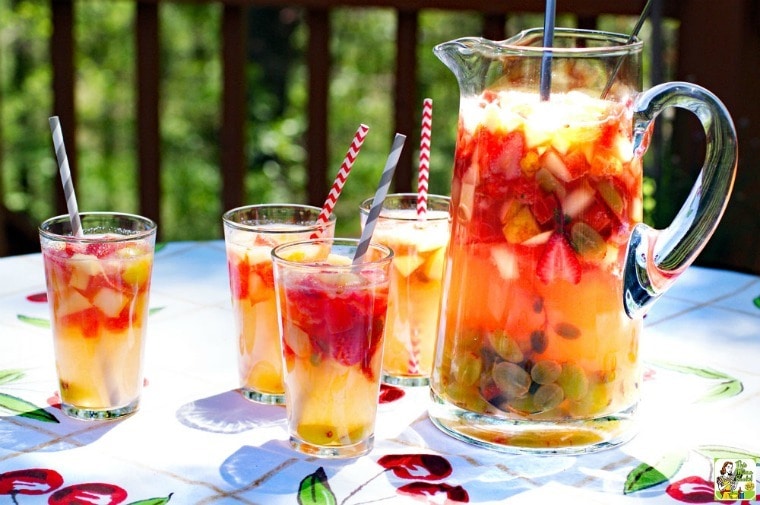 Lemonade Sangria served in glasses and picture on a table draped in a fruit patterned tablecloth.