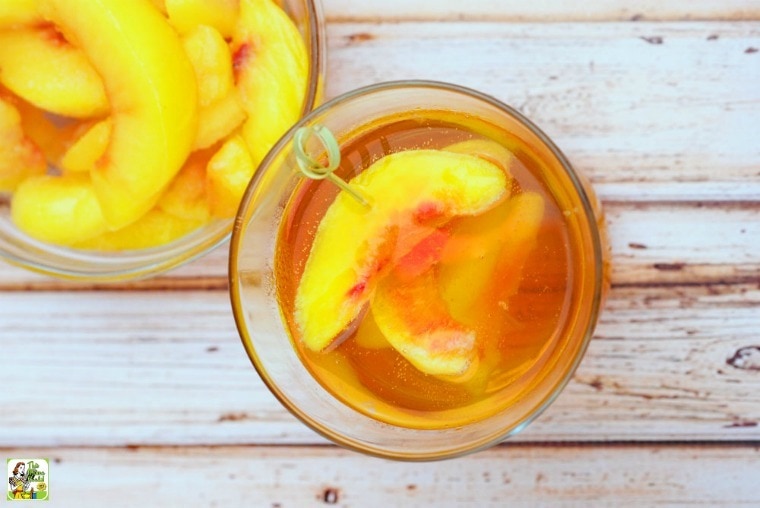 Overhead shot of two peach whiskey cocktails in glasses filled with peach slices.