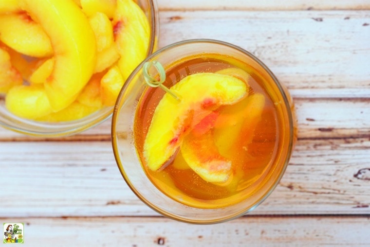 Overhead shot of two peach whiskey cocktails in glasses filled with peach slices.