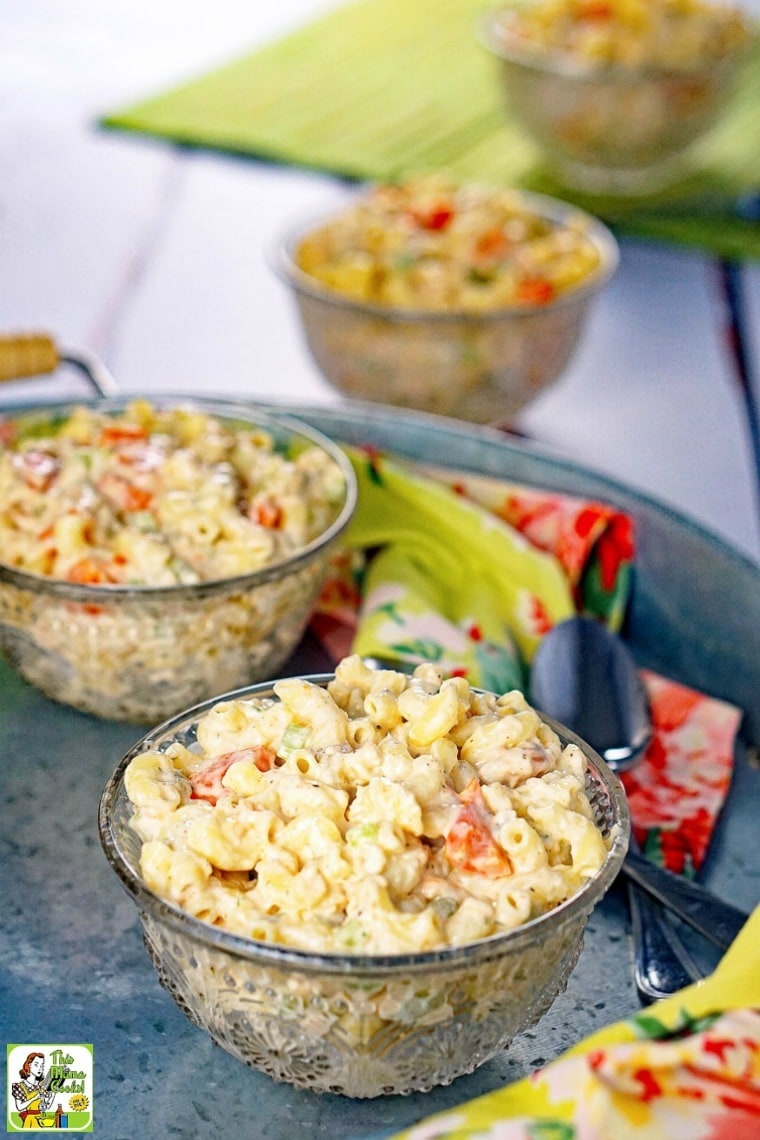 Bowls of Seafood Pasta Salad on a metal tray with floral napkins and spoons.
