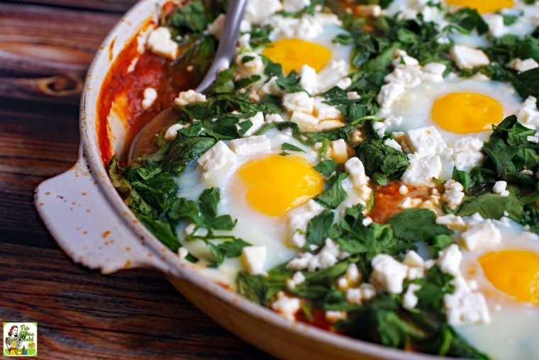 Closeup of skillet of shakshuka with serving spoon.