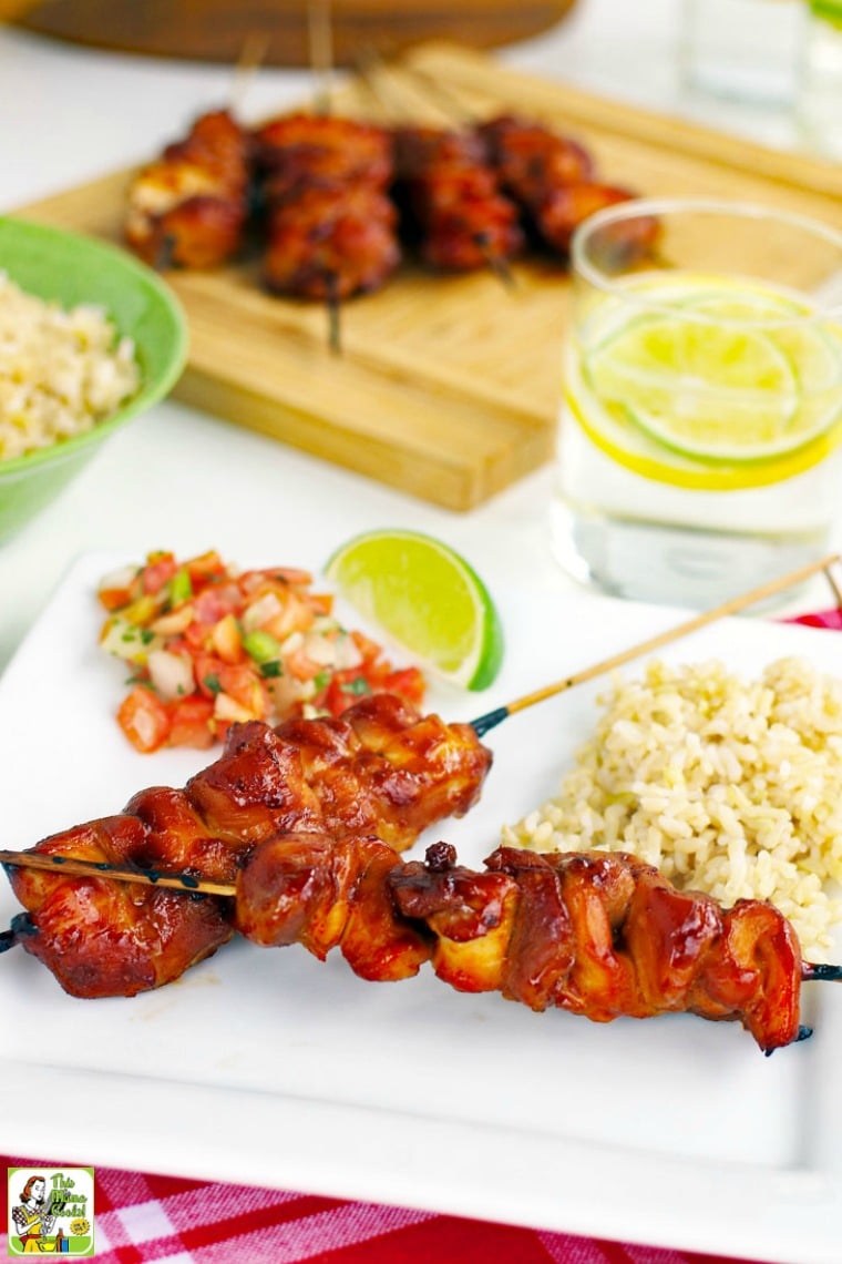 Skewers of Chicken Kabobs on a white plate with salsa and rice.