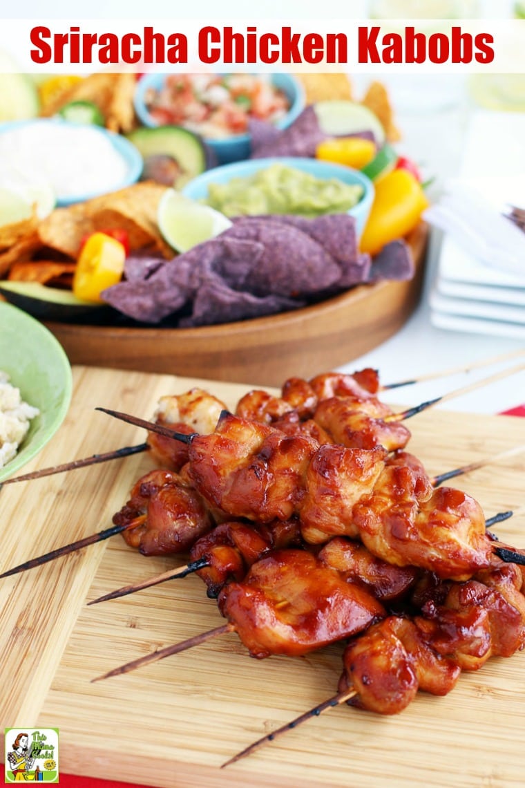 Skewers of Chicken Kabobs on a wooden platter with a wooden bowl of guacamole and tortilla chips.