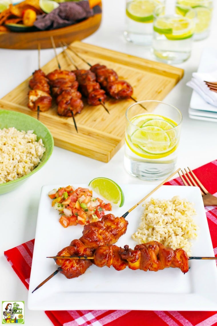 Chicken kabobs skewers, glasses of lemon water, and bowl of rice.