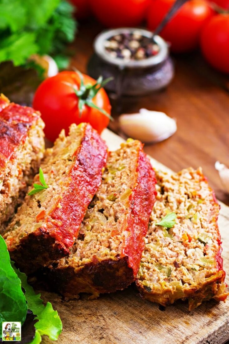 Closedup of an overhead shot of sliced meatloaf on a wooden cutting board with lettuce.