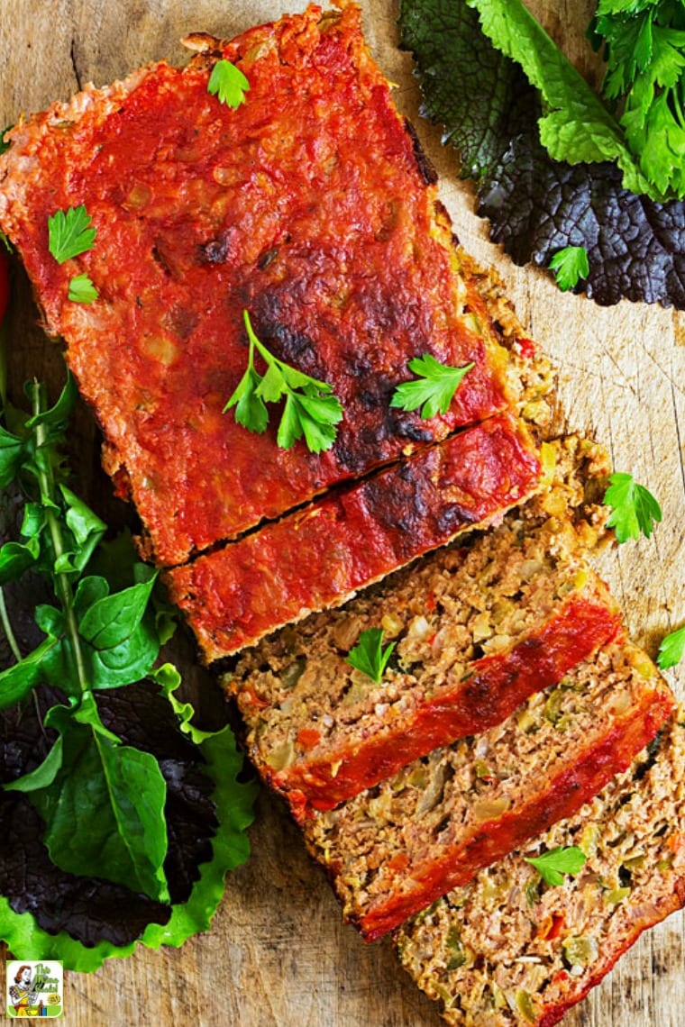 Closedup of an overhead shot of sliced meatloaf on a wooden cutting board with lettuce.