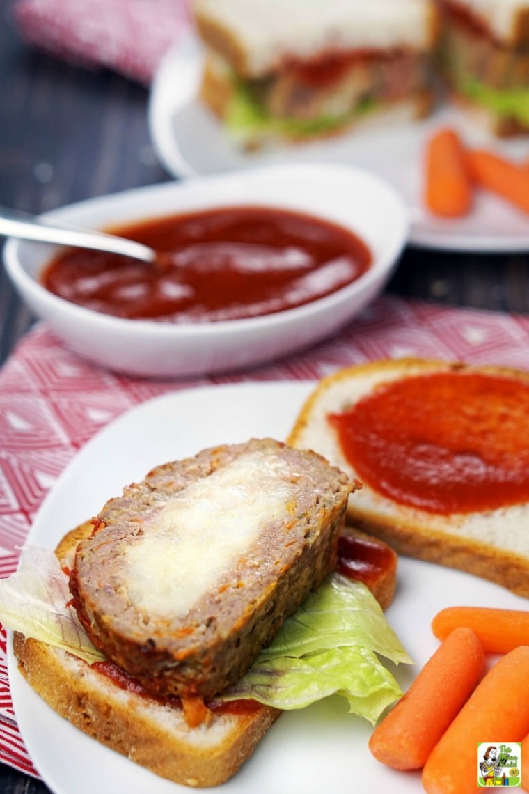 Plate of sliced mashed potato stuffed meatloaf served on bread with baby carrots.