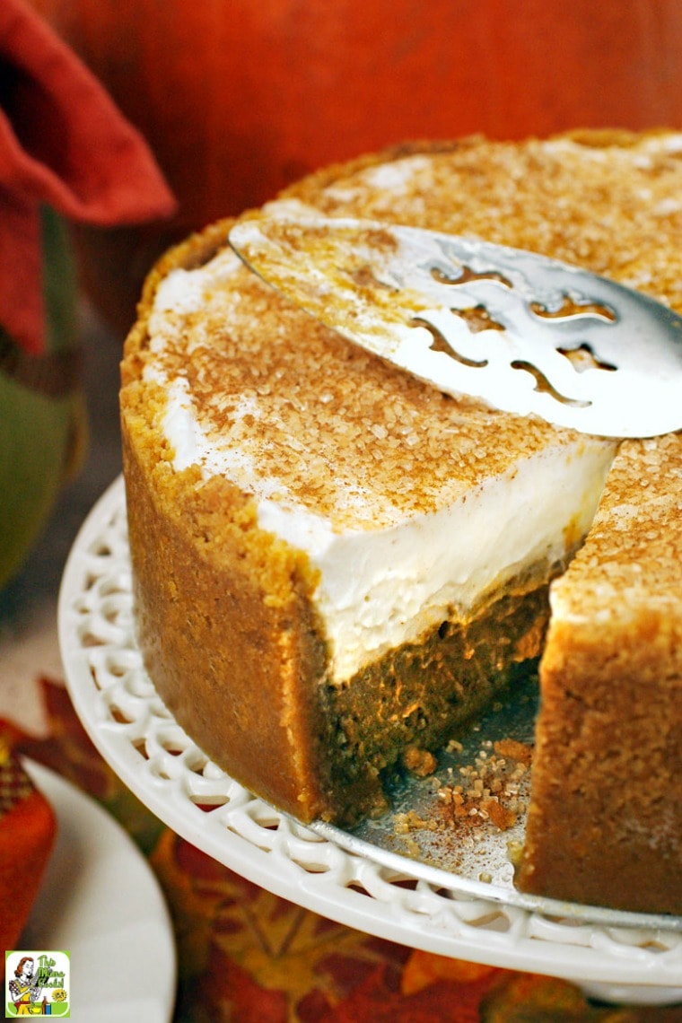 Deep dish pumpkin pie on a cake stand with a serving spoon.