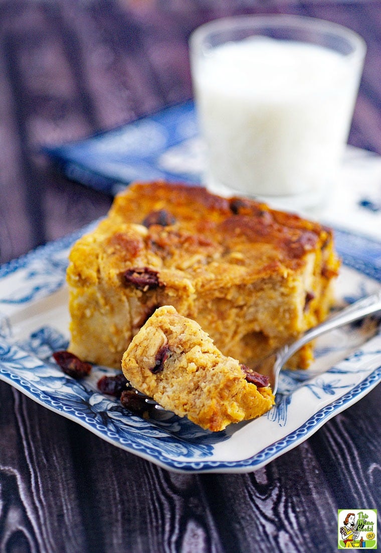 Gluten free bread pudding recipe with pumpkin on a blue and white plate with a fork and a glass of milk in the background.