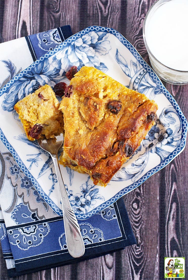 Overhead shot of gluten free bread pudding recipe on a blue and white plate with a fork and a glass of milk.