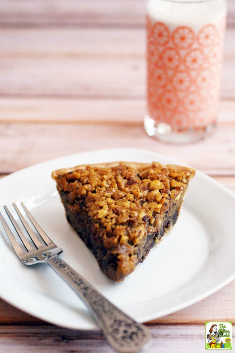 A slice of Chocolate Pecan Pie on a white plate with a silver fork with a glass of milk in a vintage glass.