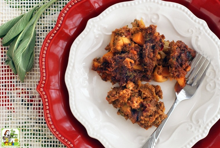 Gluten Free Stuffing Recipe with Chorizo, Squash & Apples on a white and red plates with fork and a sprig of sage.
