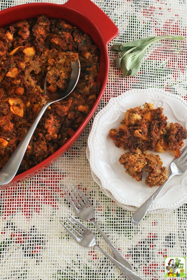 A holiday plate and casserole dish of gluten free stuffing with shorizo, squash and apples with forks.
