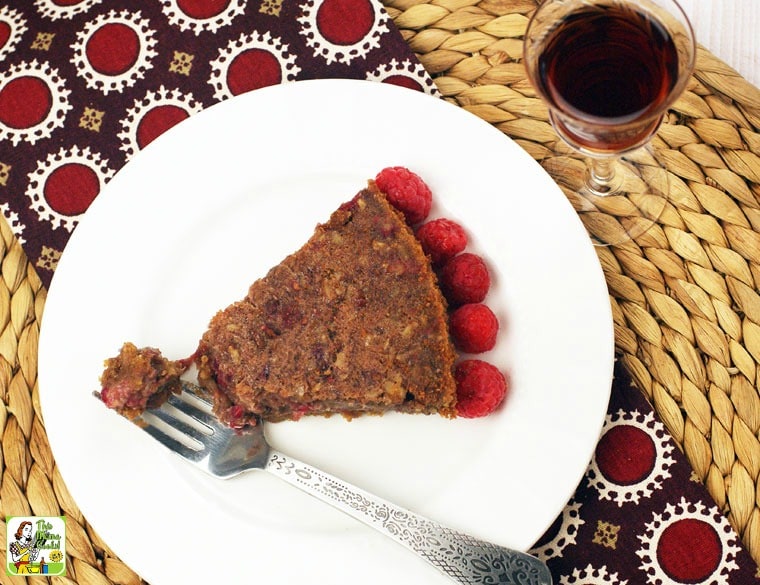 Overhead of a slice of gluten free pecan pie on a white plate with a fork and a glass of port.