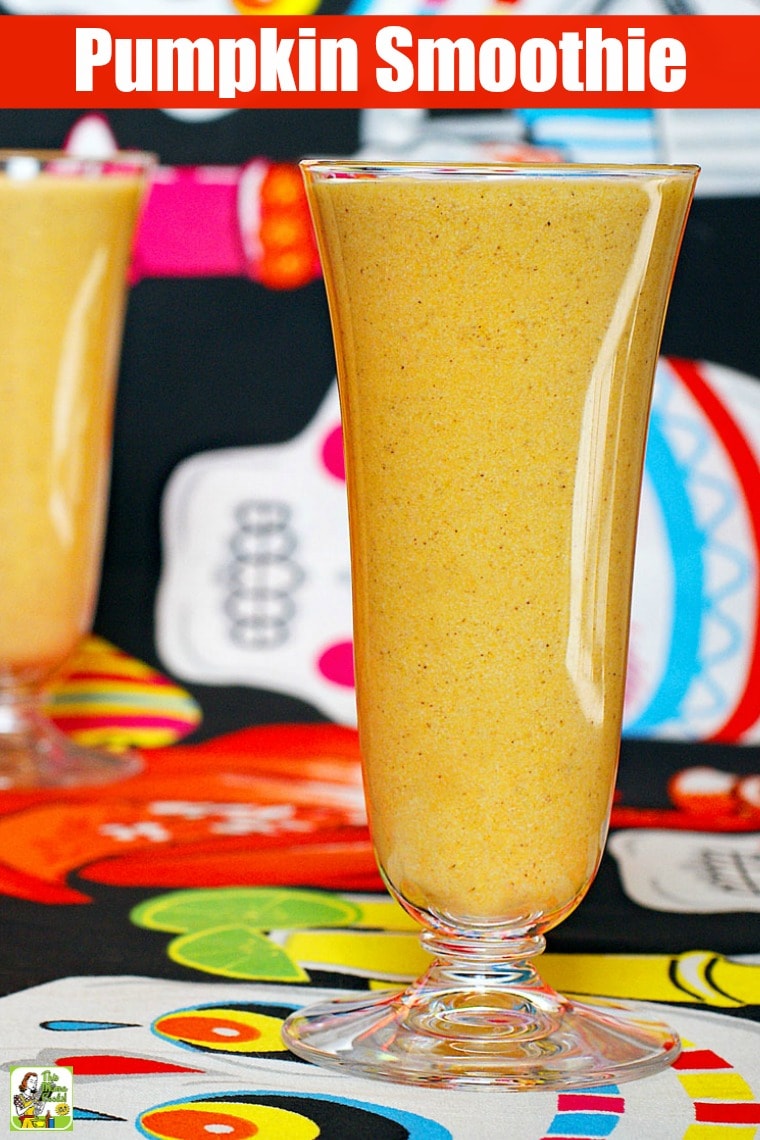 Closeup of a tall glass of pumpkin smoothie on a day of the dead tablecloth.