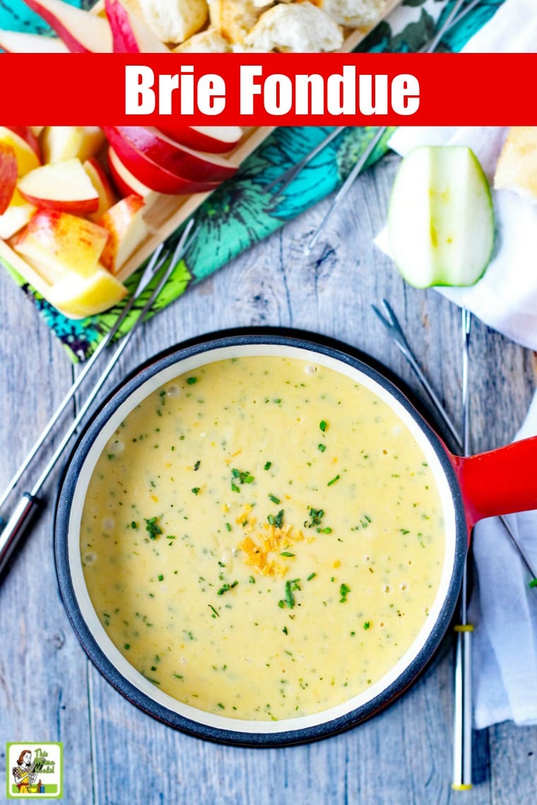 A pot of brie fondue and fondue forks with dipping foods.