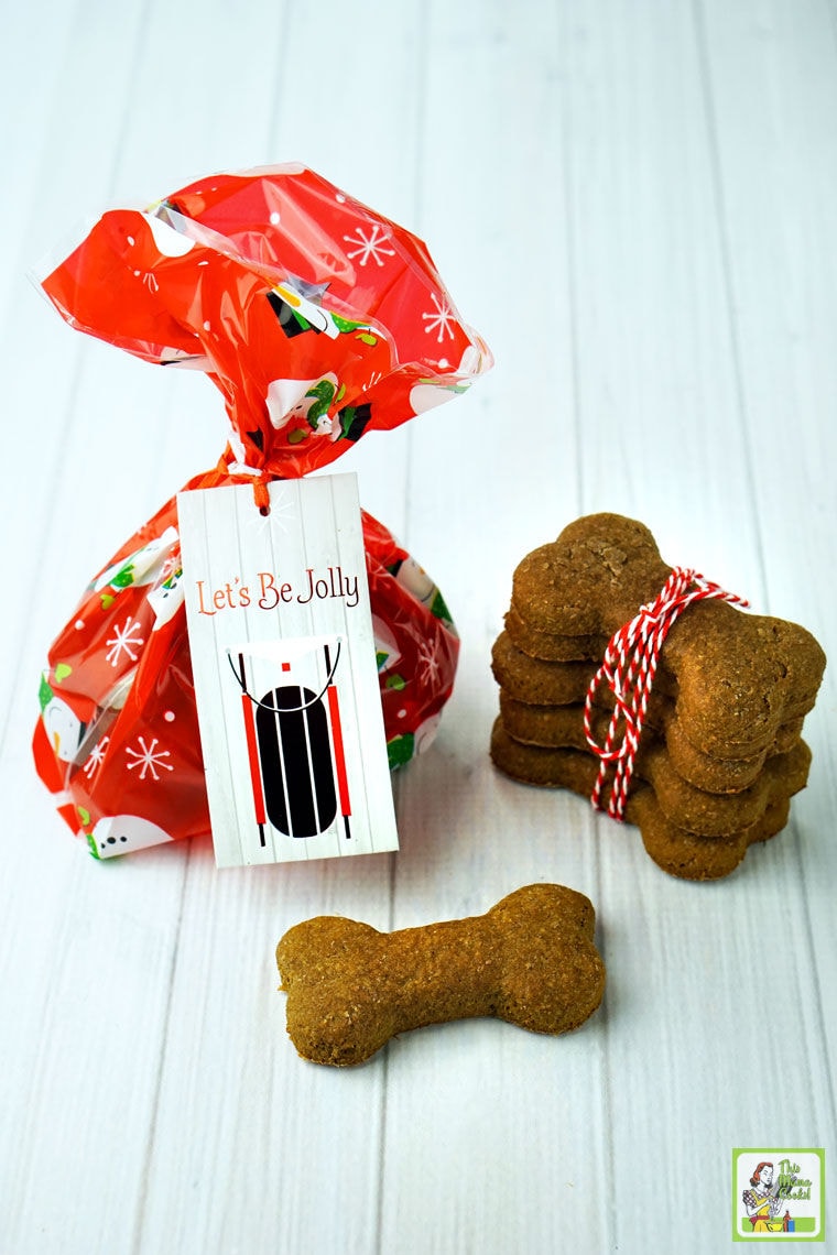 Dog bone shaped biscuits wrapped in red string and wrapped up in a festive bag with a gift tag.