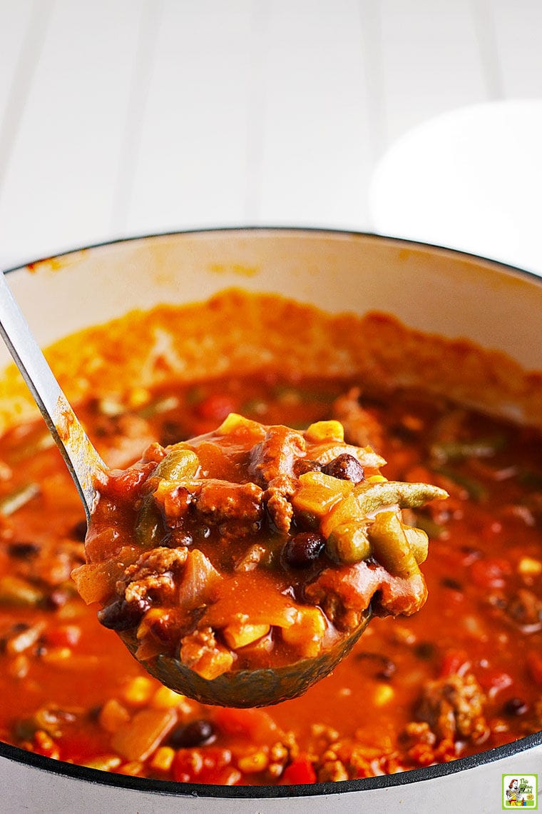 Closeup of a ladle of taco soup over a Dutch oven of taco soup.