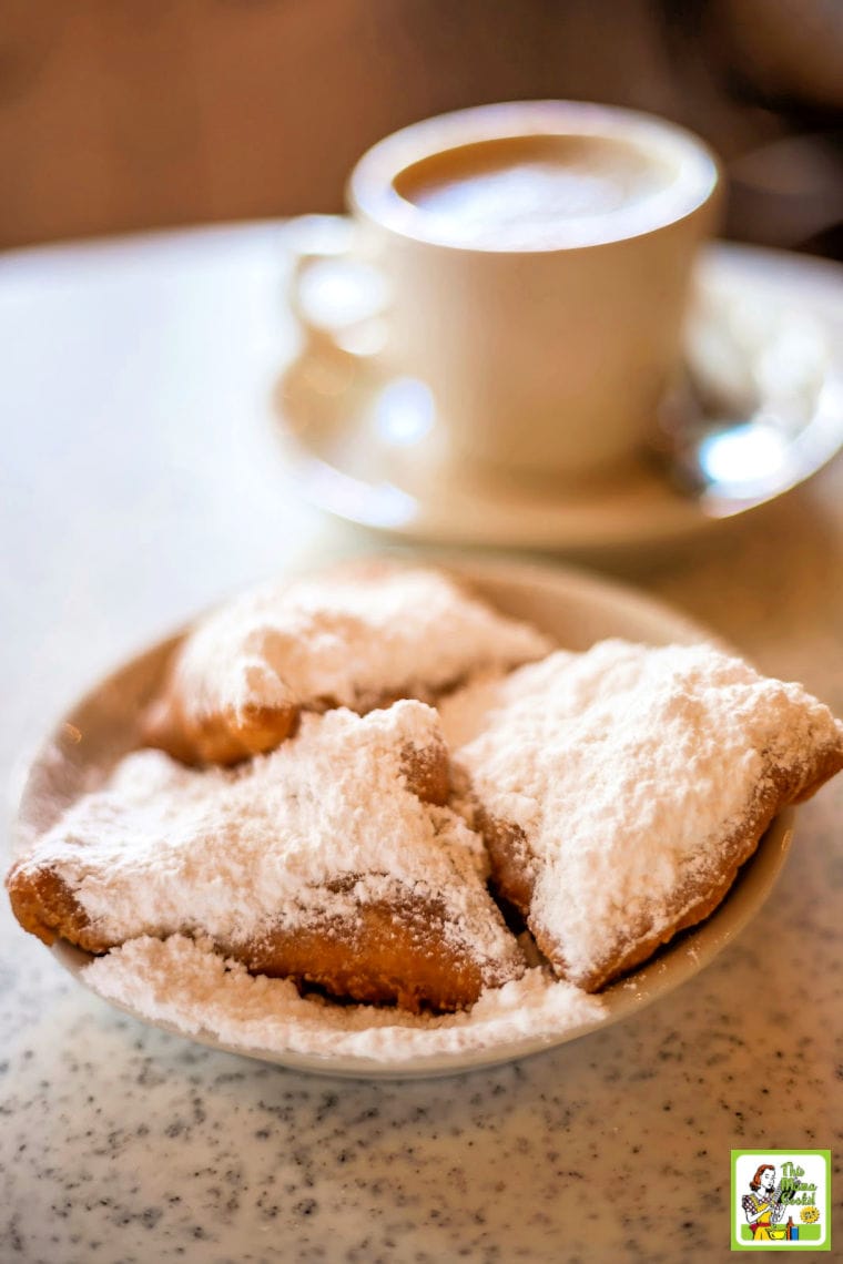 Beignets (French style donuts) topped with sugar and a cup of coffee in the background