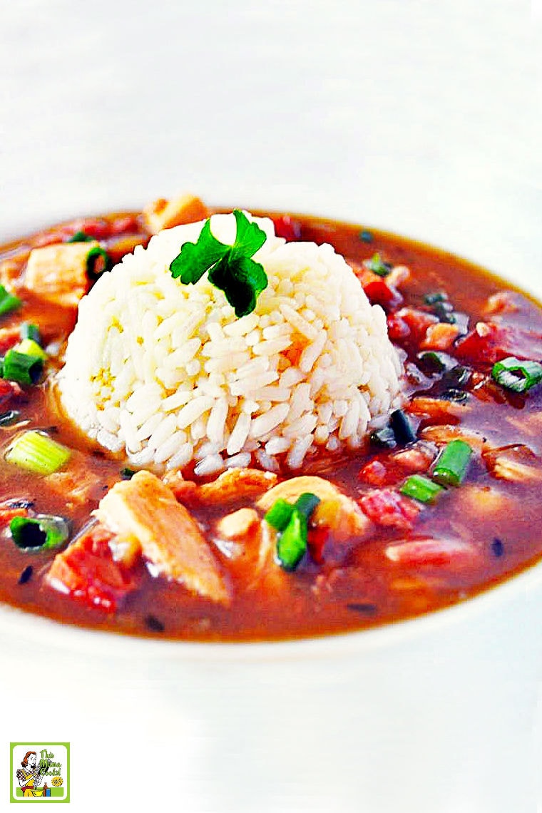 A bowl of chicken and sausage gumbo served on brown rice.