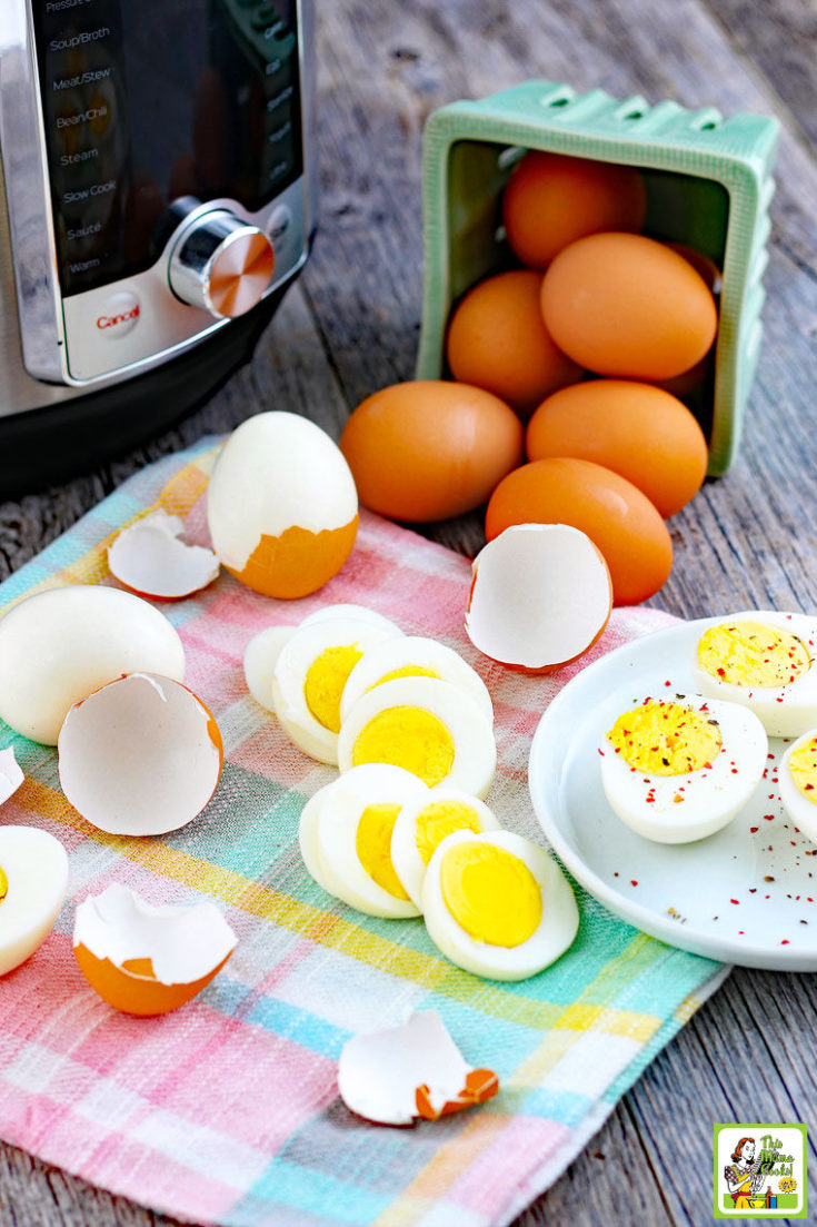 An instant pot pressure cooker with sliced and whole hard boiled eggs, brown eggs and white eggs on a plaid napkin and white plate.