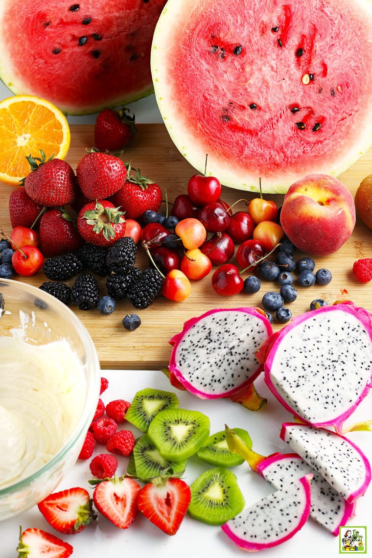 Fruit, berries, sliced fruit and a bowl of cream cheese frosting for Watermelon Pizza 