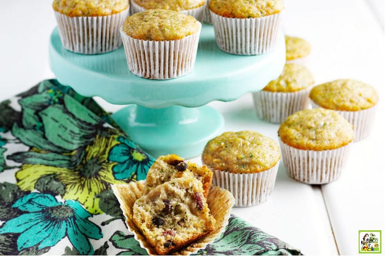 Gluten free zucchini muffins on a mint colored cake stand and a floral napkin.