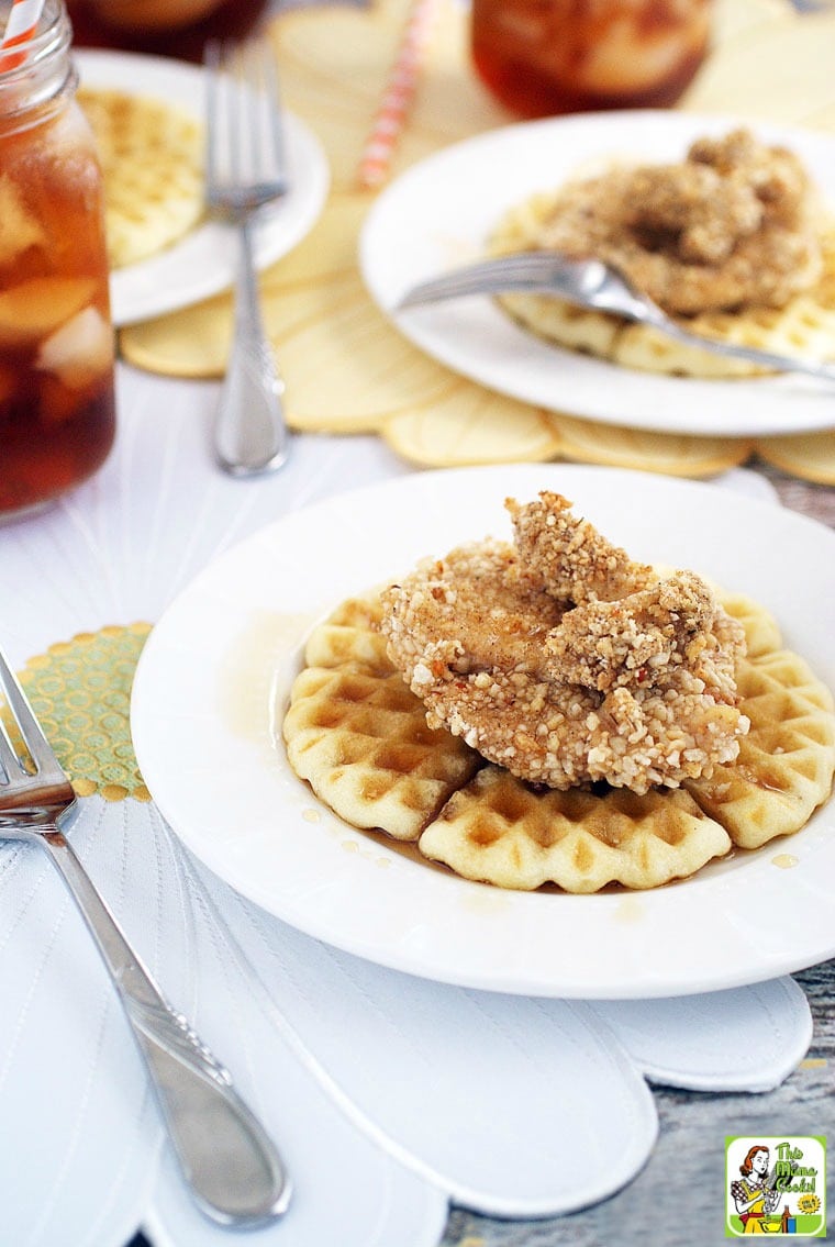 Chicken and waffles covered in maple syrup on a white plate.