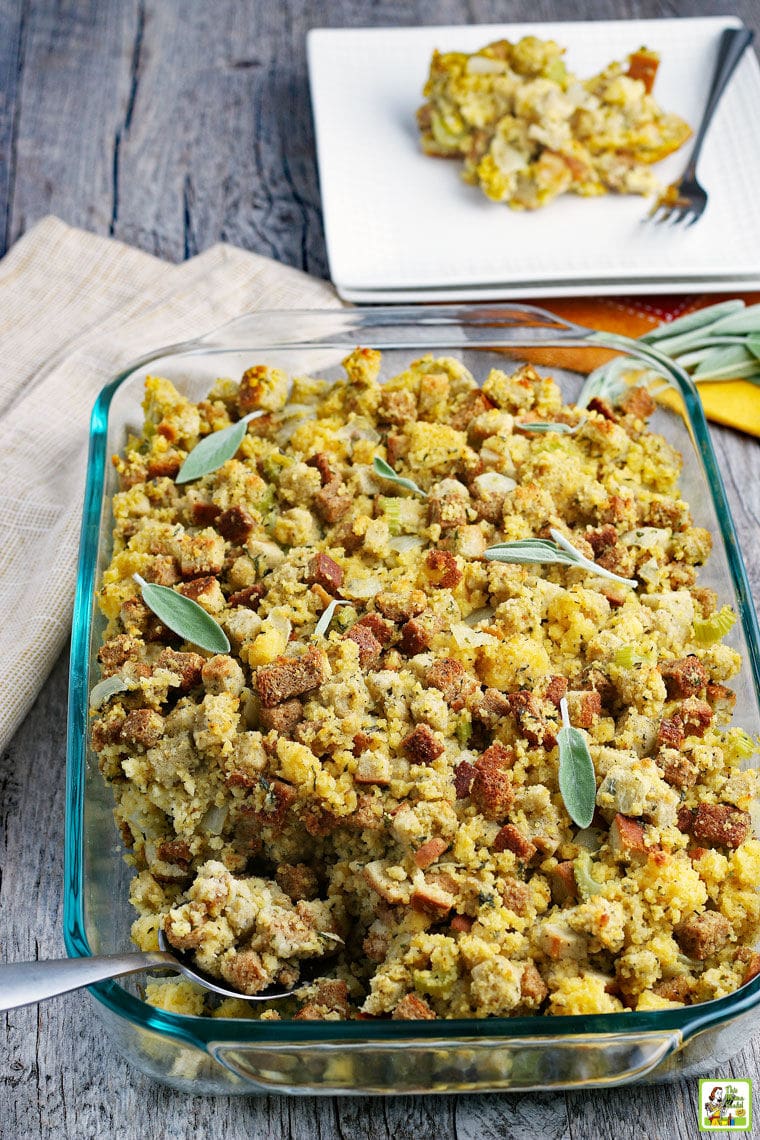 A glass pan of Cornbread Stuffing with plates and napkins.