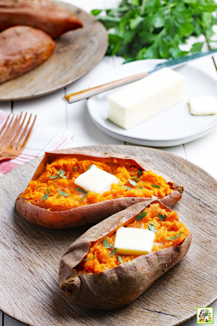 Cooked sweet potatoes on a brown plate with forks and pats of butter.