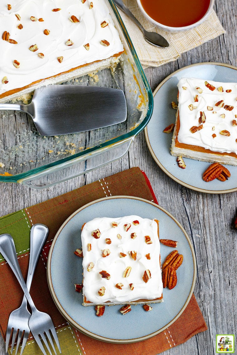 Baking dish and blue plates Pumpkin Cheesecake Lasagna dessert with napkins, forks and caramel sauce in a bowl.