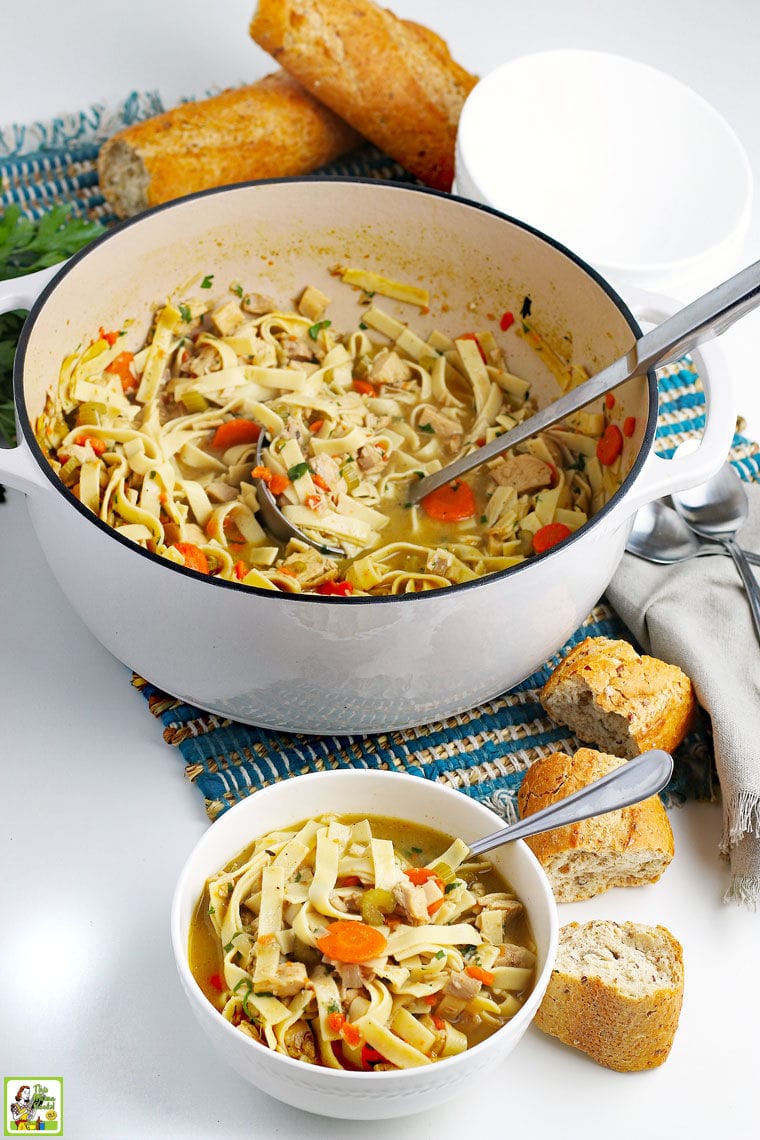 A Dutch oven and bowl of Leftover Turkey Soup with spoons and bread.