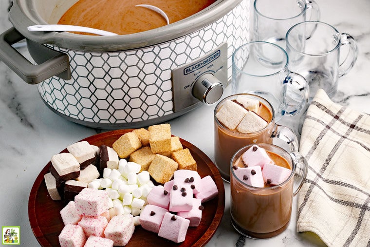 Crockpot hot chocolate made in a slow cooker served with marshmallows in glass mugs.