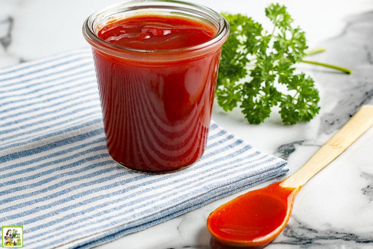 Sugar Free BBQ Sauce in a glass jar with a serving spoon, napkin and parsley.