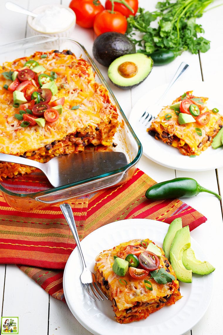 Chicken enchiladas in a casserole dish and on white plates with avocados on striped napkins.