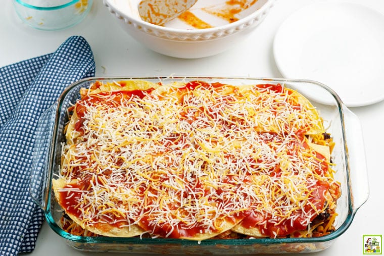 The final layer of the chicken enchilada casserole in a glass baking dish.