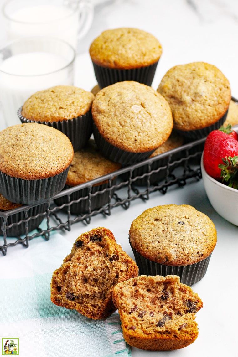 Closeup of a broken muffin and a basket of applesauce muffins with a bowl of strawberries.