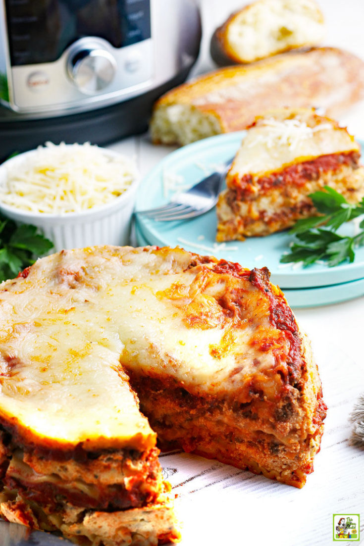 Instant Pot lasagna with a slice on a blue plate with a fork, bread, and a bowl of shredded cheese.