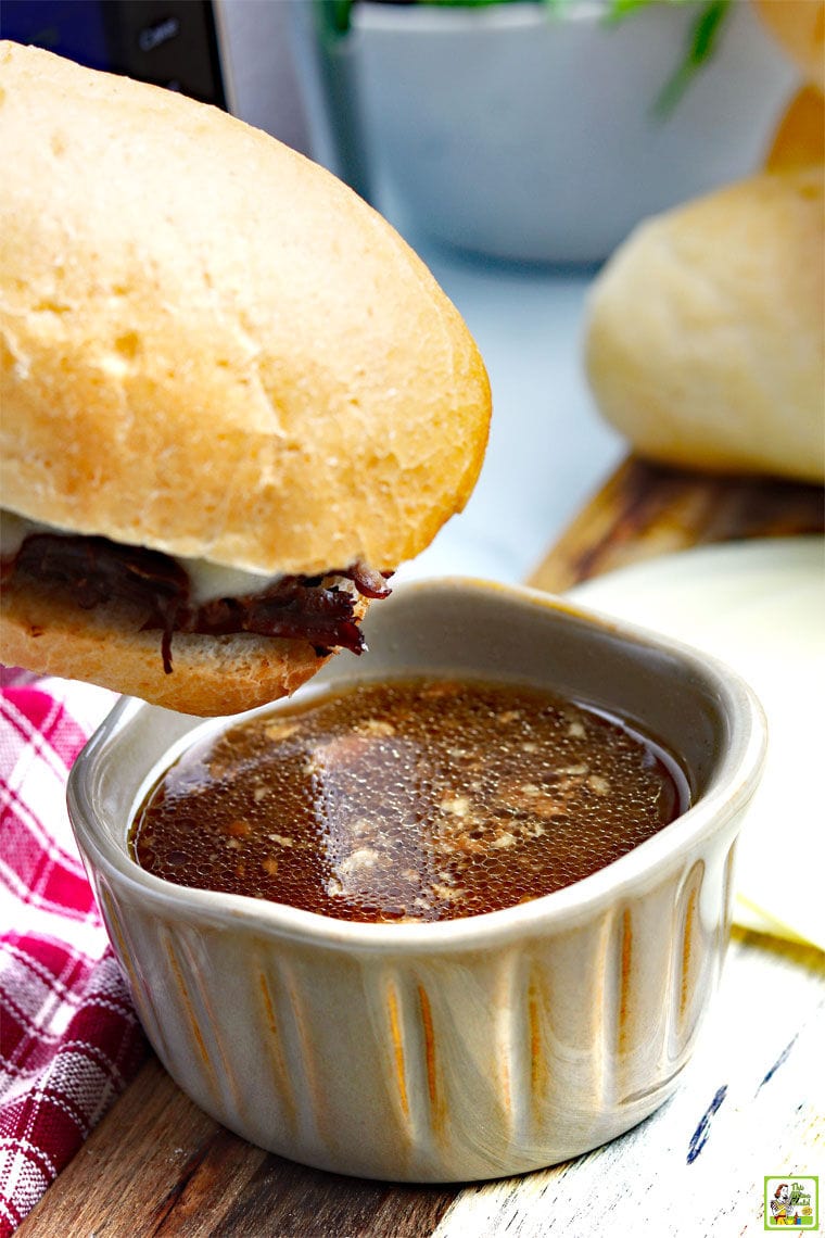 End of a Instant Pot French Dip Sandwich dipping into a ramekin of au jus.