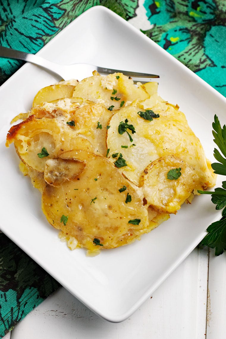 Overhead shot of crockpot scalloped potatoes with fork on a floral napkin.